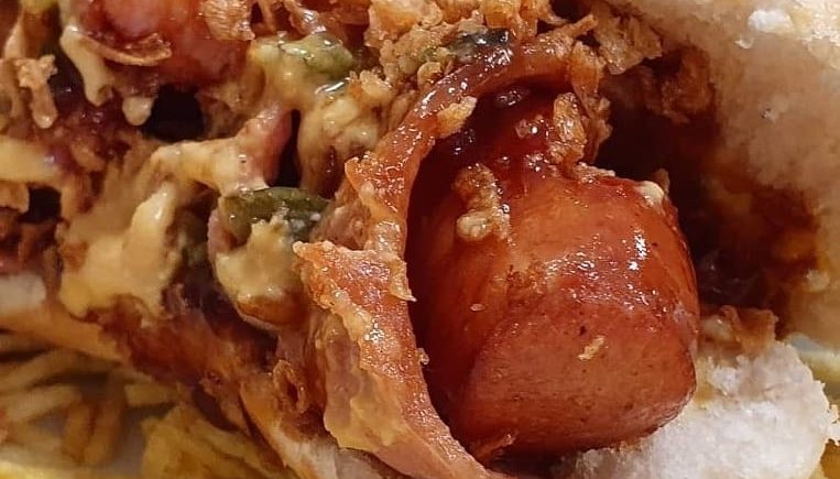 Hotdog Brooklyn, pan, salchicha bockwurst en bacon con salsa cheddar, bbq.. a domicilio en La Marmita Street Food de Cádiz