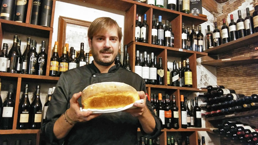 Javier Muñoz el jefe de cocina de La Carboná en la bodega de su restaurantes posando con un pan que realiza con velo de flor. Foto: Cosasdecome